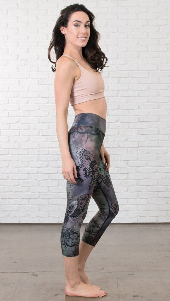 right side view of model wearing capri printed leggings with gothic moths, gargoyles, skulls, ravens design