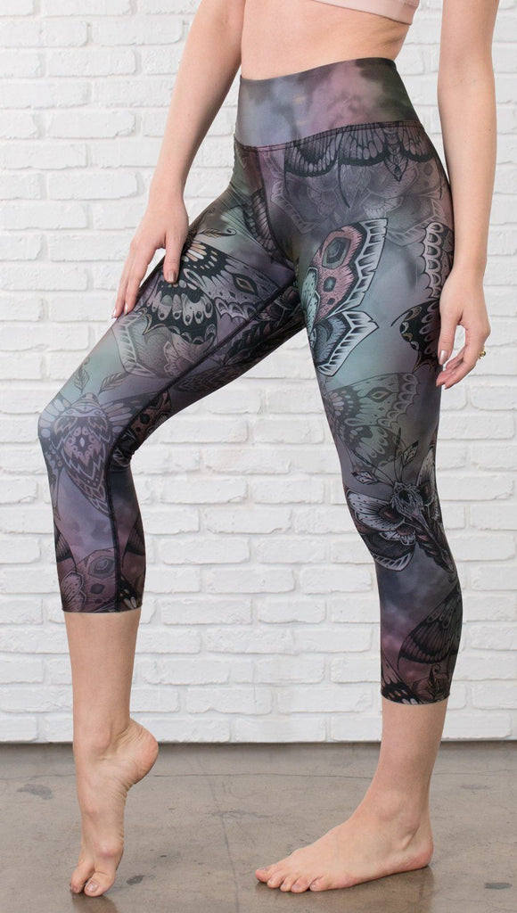 closeup left side view of model wearing capri printed leggings with gothic moths, gargoyles, skulls, ravens design