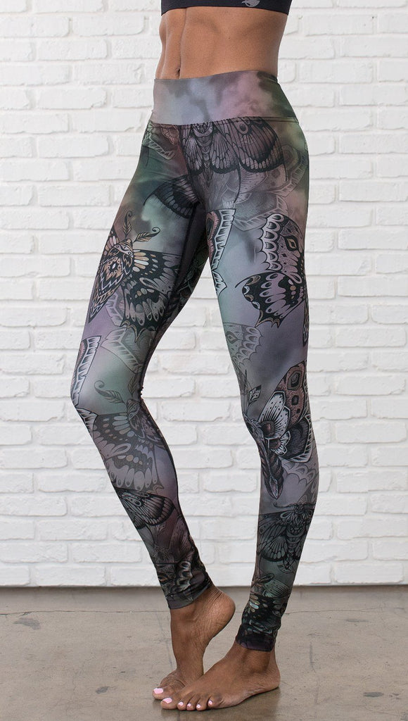 closeup front view of model wearing full length printed leggings with gothic moths, gargoyles, skulls, ravens design