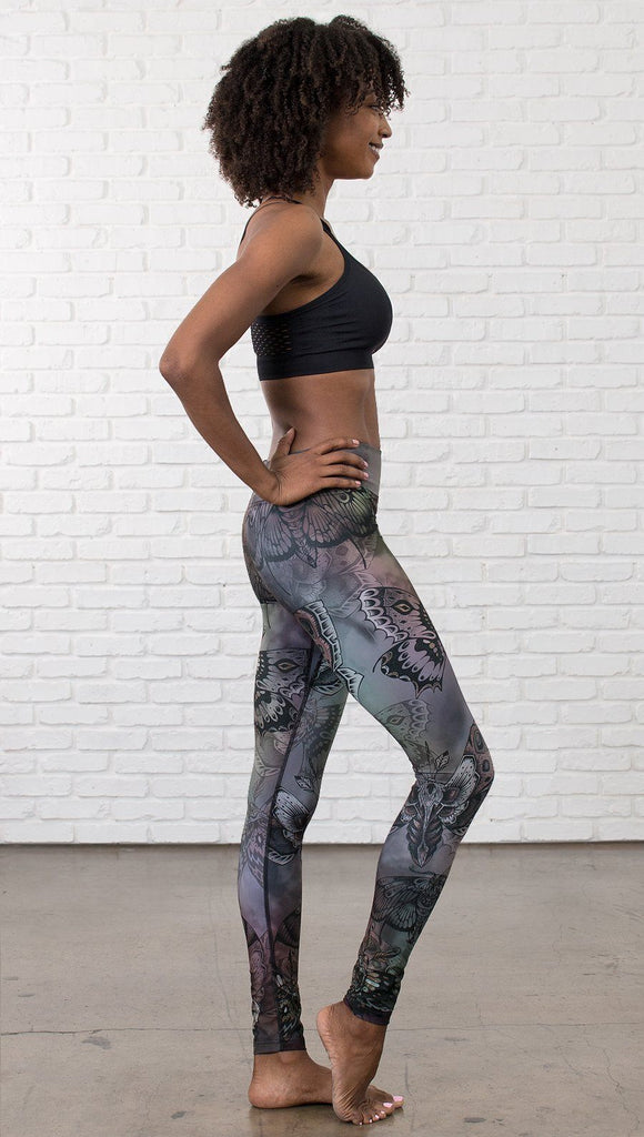 right side view of model wearing full length printed leggings with gothic moths, gargoyles, skulls, ravens design