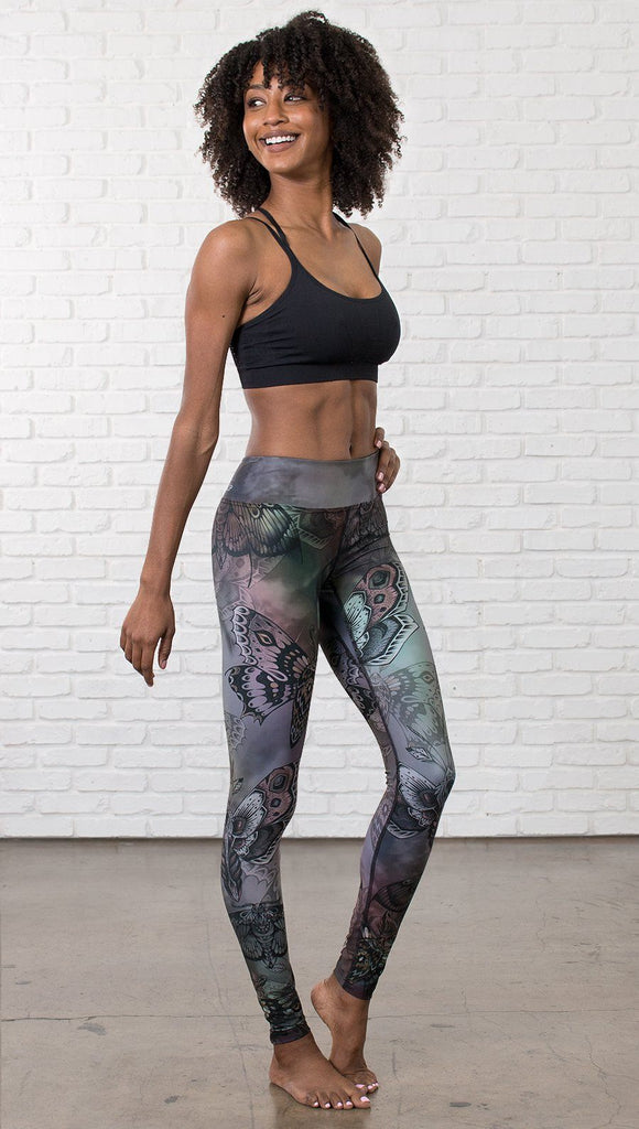 right side view of model wearing full length printed leggings with gothic moths, gargoyles, skulls, ravens design