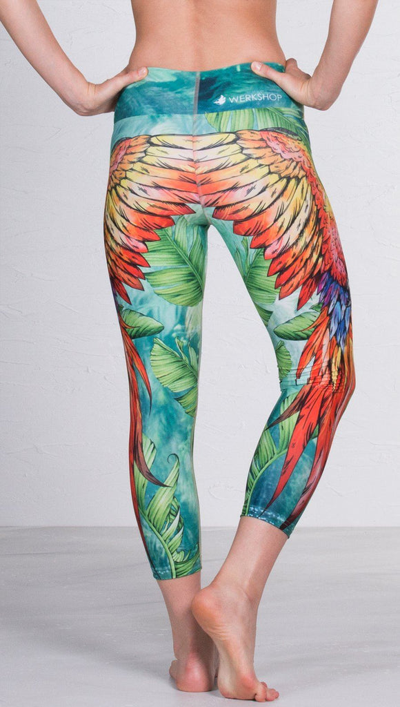 closeup back view of model wearing macaw themed capri leggings