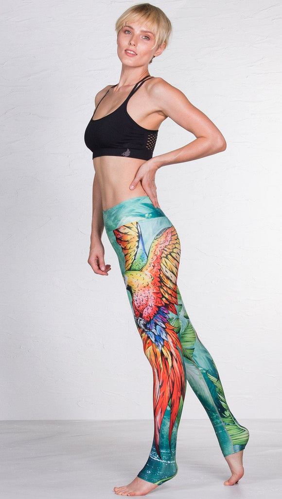 left side view of model wearing macaw themed full length leggings