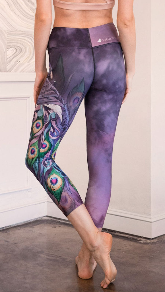 back view of model wearing peacock themed capri leggings