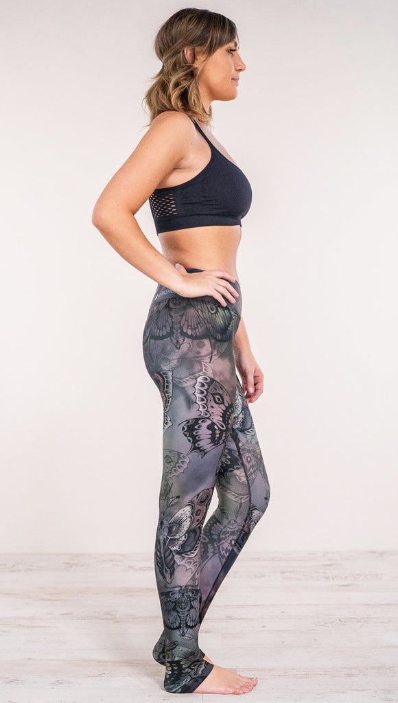 Right side view of model wearing full length printed leggings with gothic moths, gargoyles, skulls, ravens design