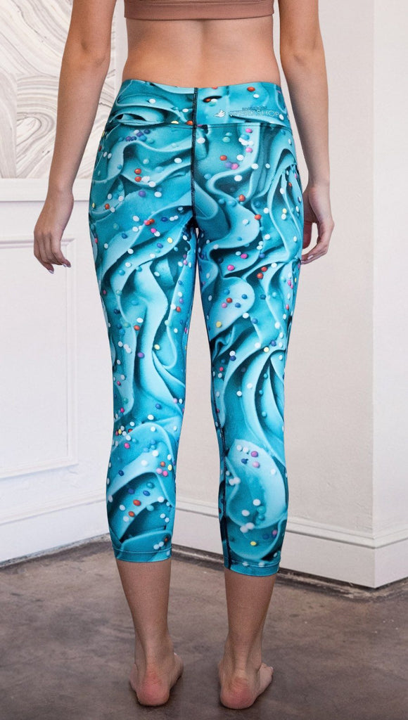 closeup front view of model wearing teal cupcake frosting themed printed capri leggings