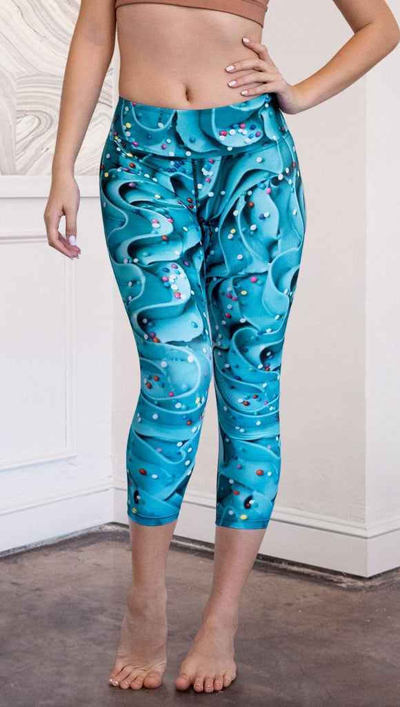 closeup front view of model wearing teal cupcake frosting themed printed capri leggings