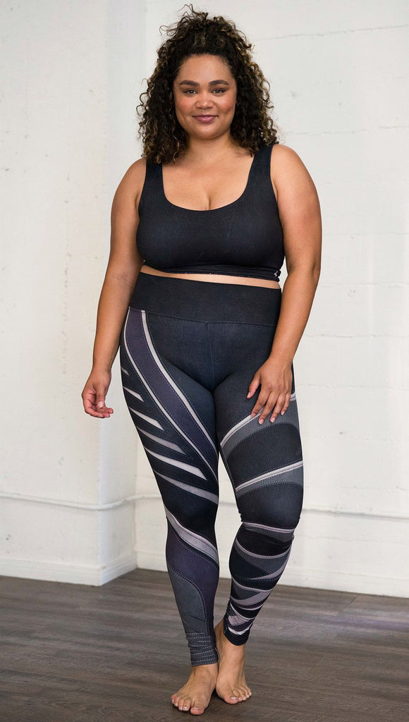 Front view of model wearing black printed full-length leggings with purple and gray stripe design