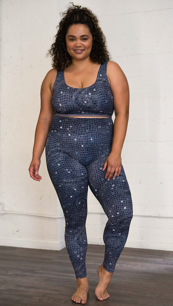 Front view of model wearing mosaic printed full length leggings with moon artwork on left hip