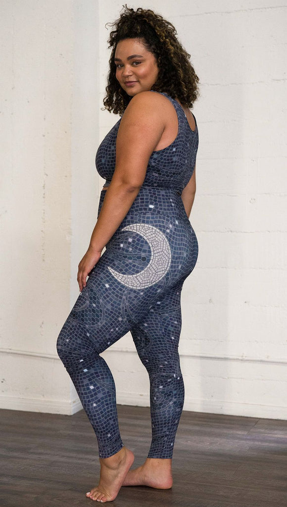 Left side view of model wearing mosaic printed full length leggings with moon artwork on left hip