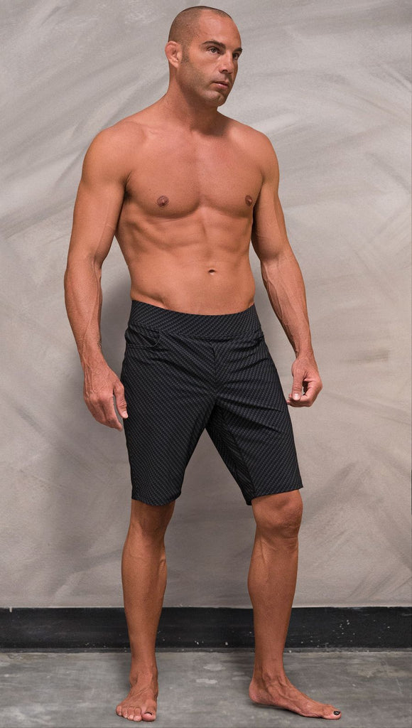 Front view of model wearing men's black printed performance shorts with slim fit and carbon fiber inspired art.