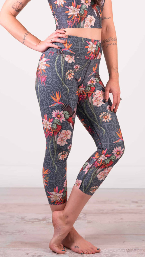 Model wearing WERKSHOP Quetzal Triathlon Capri Leggings. The leggings are printed with with original quetzal artwork with clusters of tropical flowers and birds of paradise.