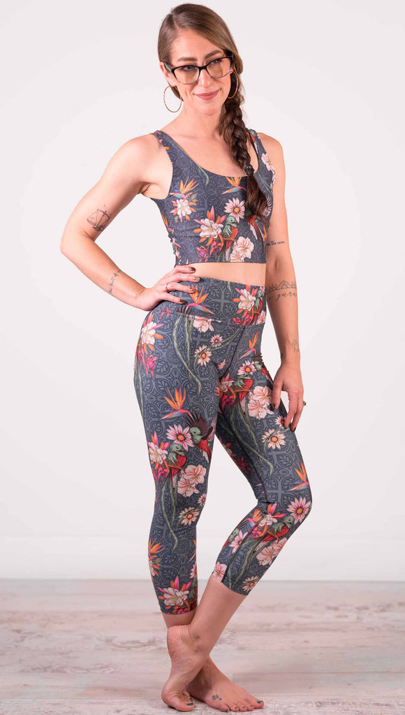 Model wearing WERKSHOP Quetzal Triathlon Capri Leggings. The leggings are printed with with original quetzal artwork with clusters of tropical flowers and birds of paradise.