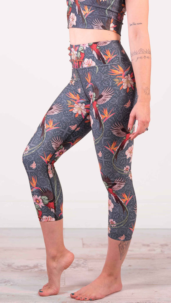 Model wearing WERKSHOP Quetzal Triathlon Capri Leggings. The leggings are printed with with original quetzal artwork with clusters of tropical flowers and birds of paradise.