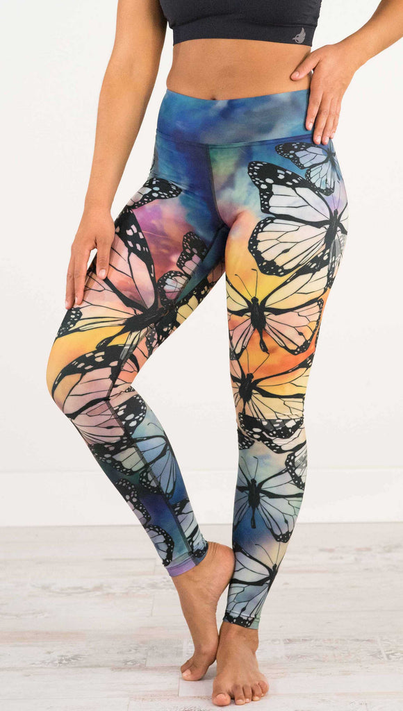 Waist down, front view of model wearing WERKSHOP Butterflies Full Length Triathlon Leggings. The artwork has a kaleidoscope of rainbow colors with black outline drawings of Monarch butterflies.