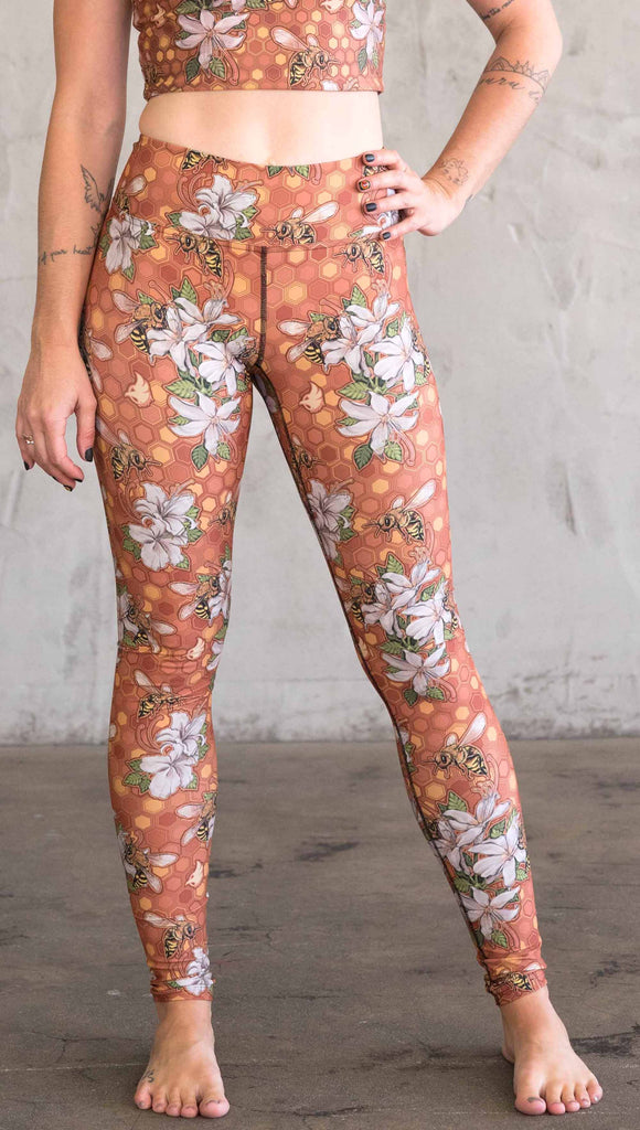 Front view of model wearing WERKSHOP Honeybees leggings in triathlon fabric. The artwork has clusters of honeybees and flowers.