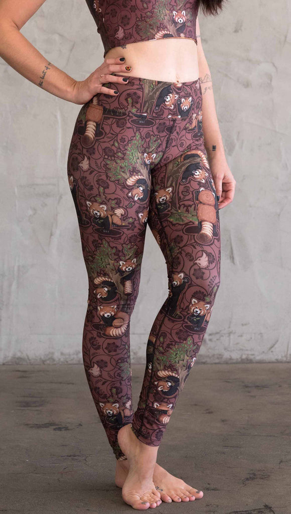 Side view of WEKSHOP red panda leggings in triathlon fabric. The artwork is dark red base with clusters of cute little red pandas playing on trees.