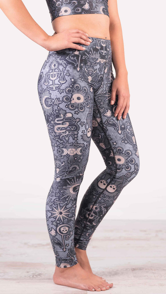 Model wearing WERKSHOP Tarot Full Length Triathlon Leggings. The blue/tarot artwork has skulls, snakes, moons and the names of multiple popular tarot cards like "Strength, Lovers, Death and The Hanged Man”. Triathlon leggings do not have pockets.