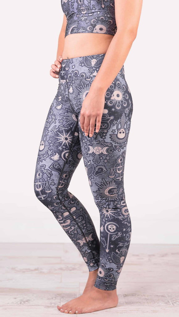 Model wearing WERKSHOP Tarot Full Length Triathlon Leggings. The blue/tarot artwork has skulls, snakes, moons and the names of multiple popular tarot cards like "Strength, Lovers, Death and The Hanged Man”. Triathlon leggings do not have pockets.