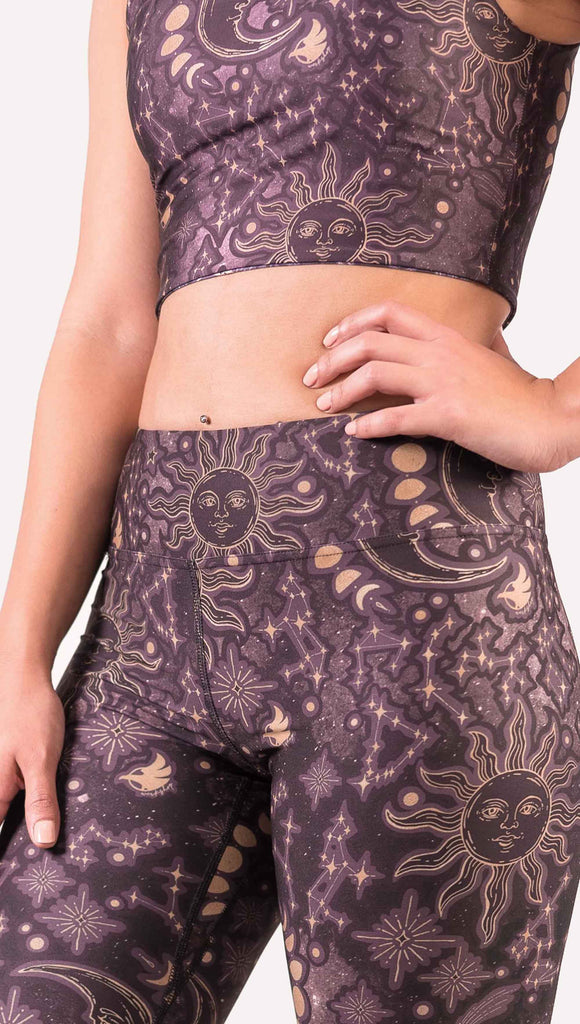 model wearing WERKSHOP Zodiac Full Length Triathlon Leggings. The zodiac themed artwork shows a hand-drawn sun and moon with the moon phases, shooting stars and all 12 zodiac constellations in gold over a dark purple background. Triathlon leggings do not have pockets.