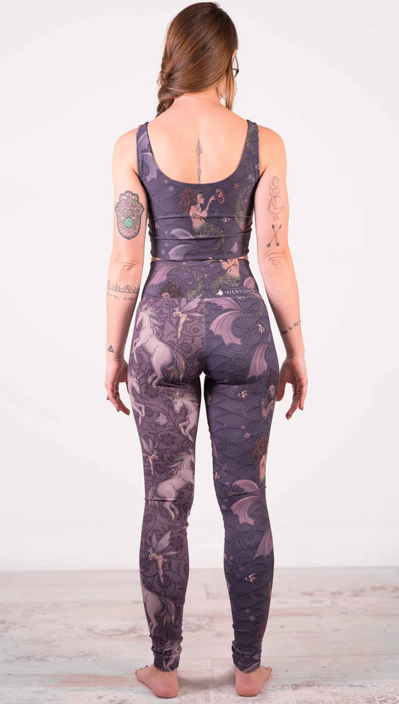 Model wearing WERKSHOP Mermaid and Unicorn Mashup Athleisure Leggings. The leggings feature mermaid artwork on the wearers right leg with a dark blue background and unicorns over a purple background on the wearer's left leg.