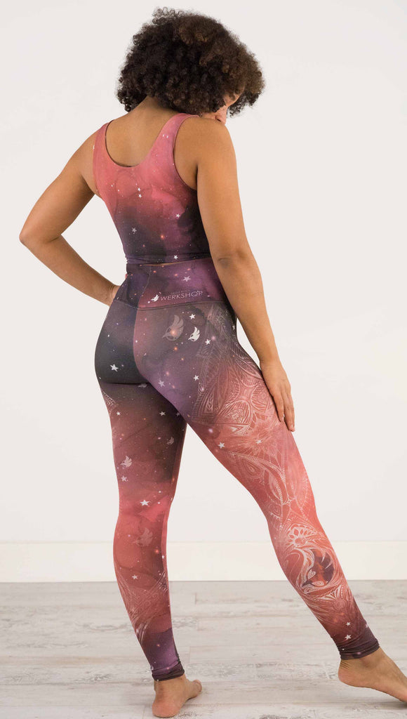 Full body back view of model wearing a red, orange and purple galaxy themed athleisure leggings with white henna inspired art running along the right side of the leg