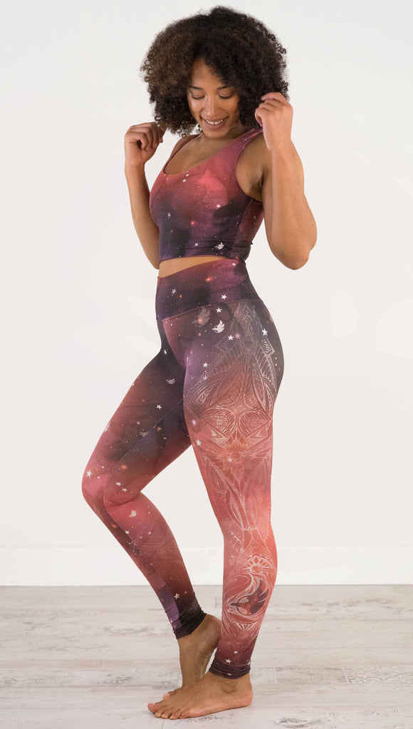 Full body side view of model wearing a red, orange and purple galaxy themed athleisure leggings with white henna inspired art running along the right side of the leg