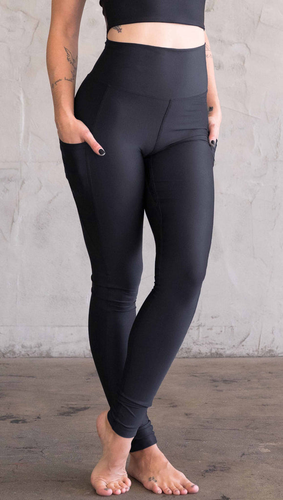 Waist down view of model wearing WERKSHOP featherlight leggings. Leggings have a small reflective eagle logo on the wearer's left pocket.