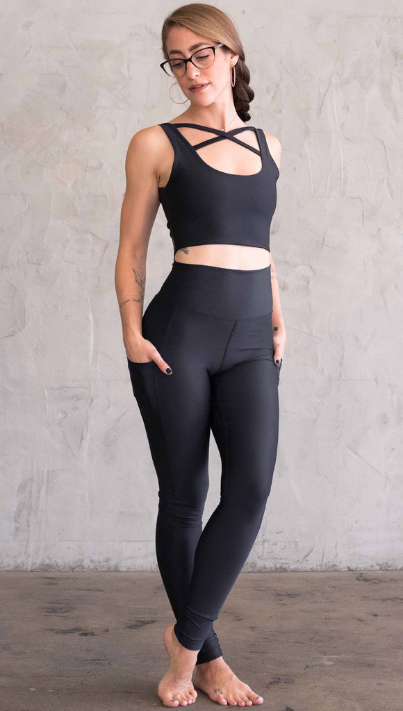 Full body view of model wearing WERKSHOP featherlight leggings. Leggings have a small reflective eagle logo on the wearer's left pocket.