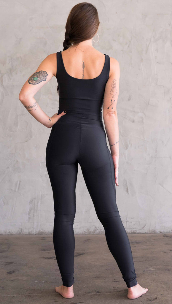 Full body back view of model wearing WERKSHOP featherlight leggings. Leggings have a small reflective eagle logo on the wearer's left pocket.