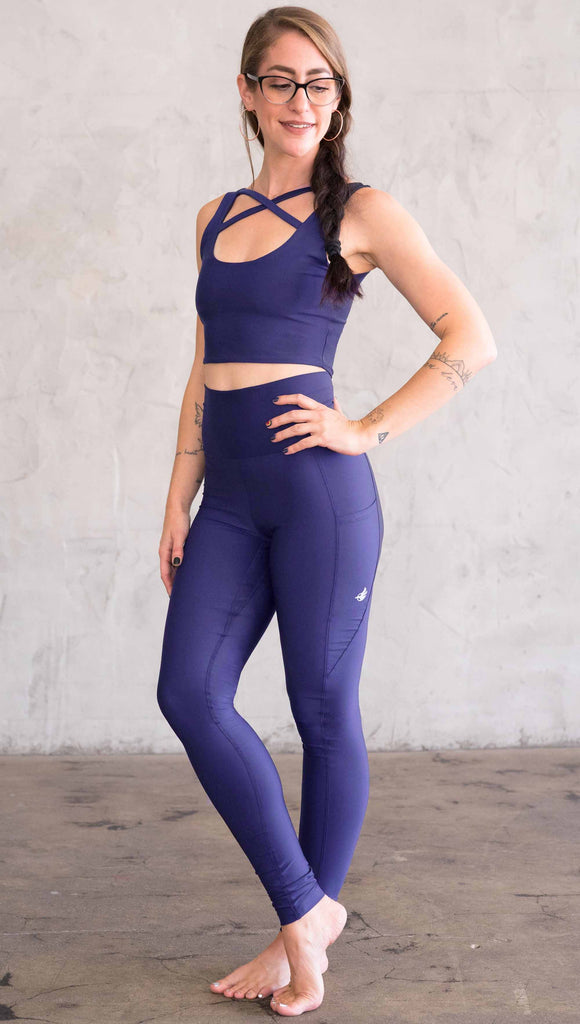 Model wearing WERKSHOP featherlight leggings in solid royal blue color. Leggings have a small reflective eagle logo on the wearer's left pocket.