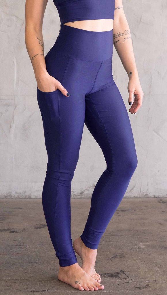 Model wearing WERKSHOP featherlight leggings in solid royal blue color. Leggings have a small reflective eagle logo on the wearer's left pocket.