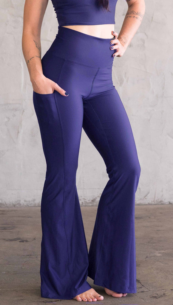 Model wearing WERKSHOP Royal Blue Featherlight Bells. They are a bright blue color with a flared leg opening, pockets on the hip, have a high waistband and a flattering long panel gusset.