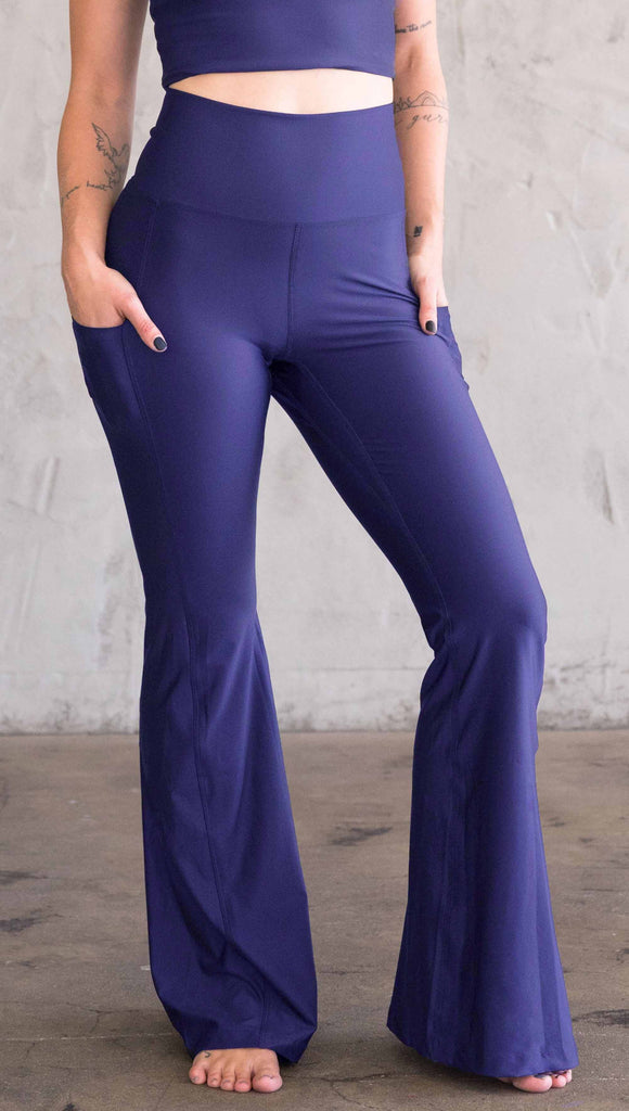 Model wearing WERKSHOP Royal Blue Featherlight Bells. They are a bright blue color with a flared leg opening, pockets on the hip, have a high waistband and a flattering long panel gusset.