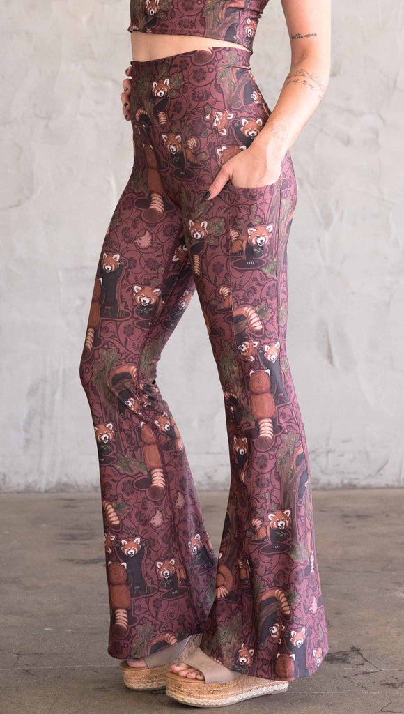 Side view of WEKSHOP red panda leggings in ultra lightweight featherlight fabric. The artwork is dark red base with clusters of cute little red pandas playing on trees and the bottoms have a large phone pocket on each leg.