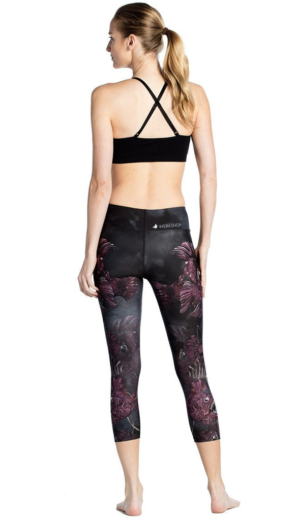 rear view of model wearing deep sea angler fish printed capri leggings and black sports top