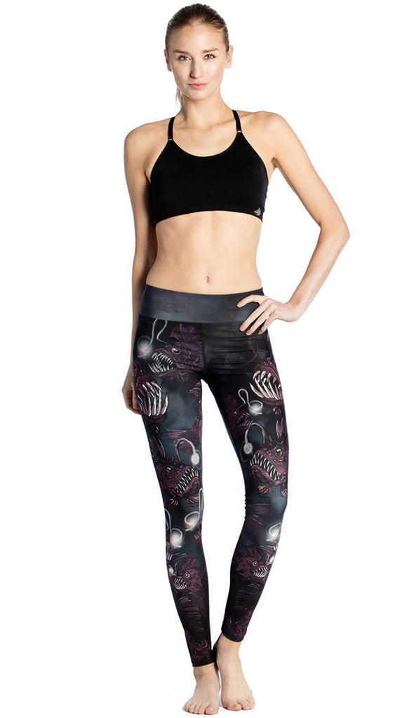 front view of model wearing deep sea angler fish printed full length leggings and black sports top