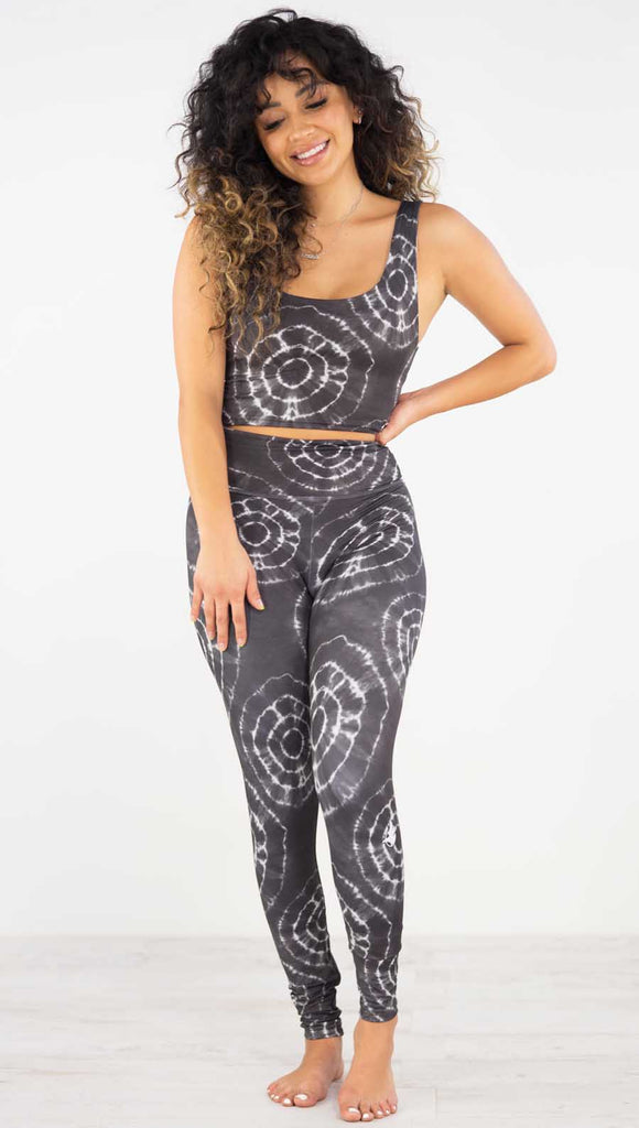 Front view of model wearing the charcoal athleisure leggings. It is in a charcoal color and has white tie dye circles throughout. Each circle has a smaller circle within each other