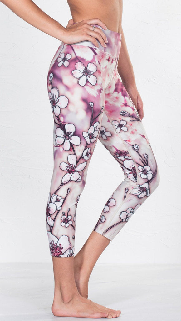 closeup right side view of model wearing cherry blossom themed printed capri leggings