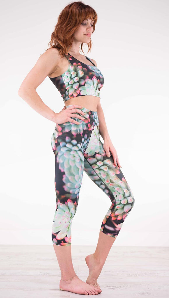 Right view of model wearing black capri leggings with green succulent plants with pink tips throughout and the matching top