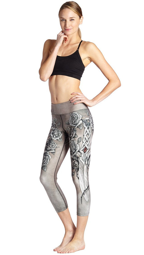 front view of model wearing sword and roses themed printed capri leggings