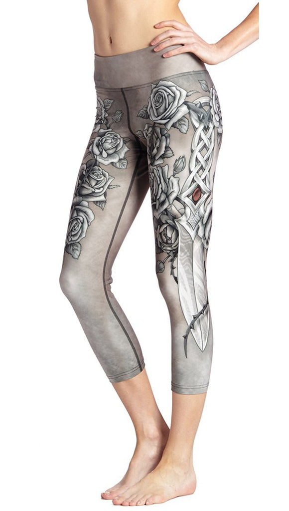 close up side view of model wearing sword and roses themed printed capri leggings