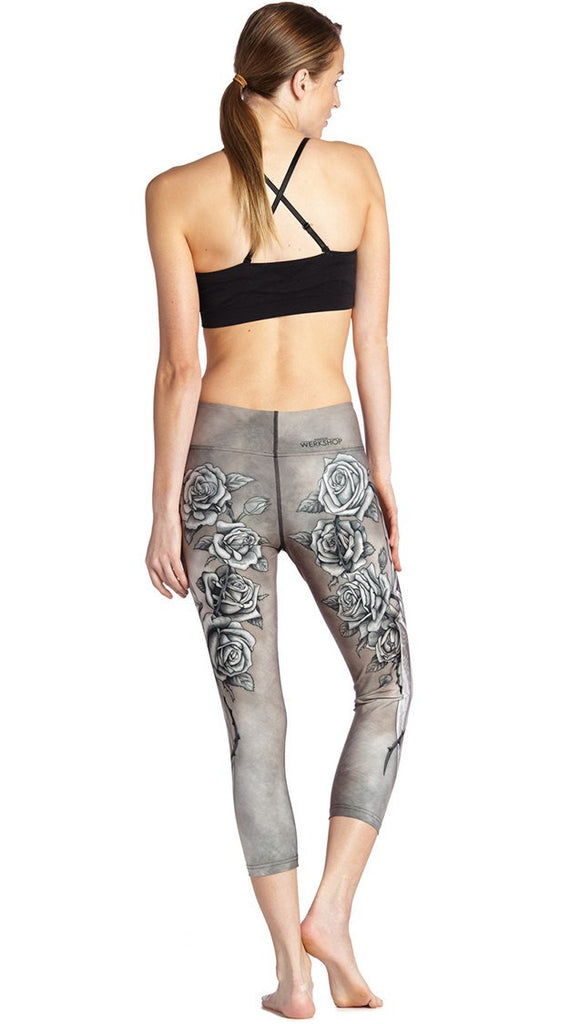 back view of model wearing sword and roses themed printed capri leggings