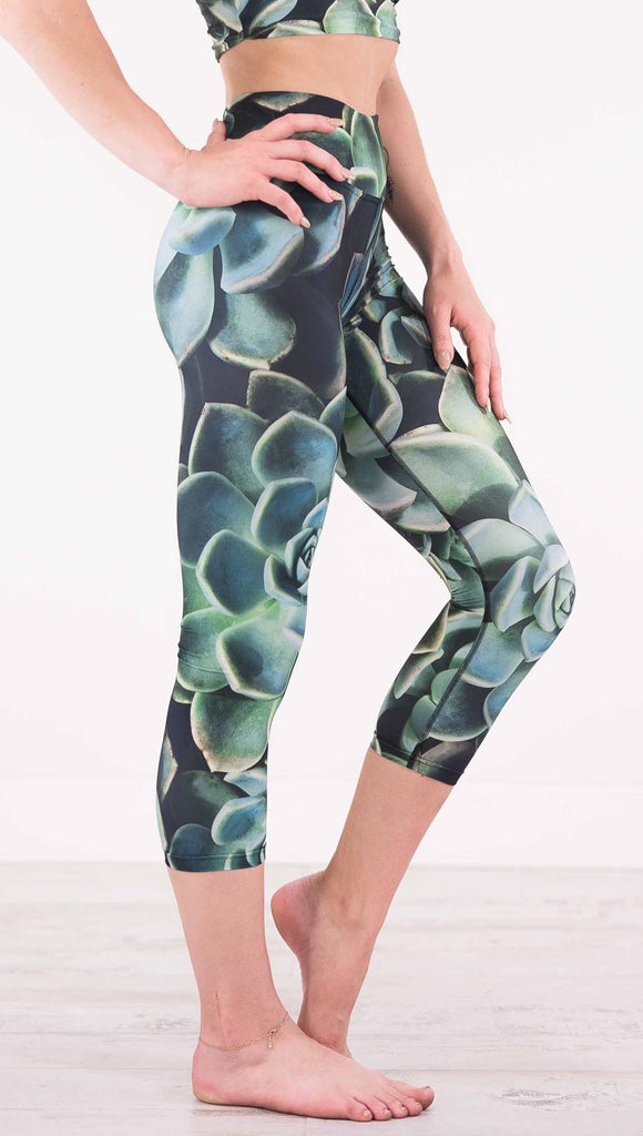 Right view of model wearing black capri leggings with green succulent plants throughout