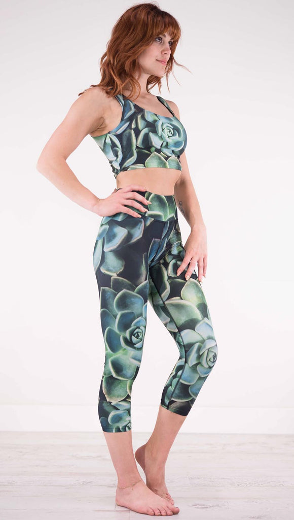 Right view of model wearing black capri leggings with green succulent plants throughout