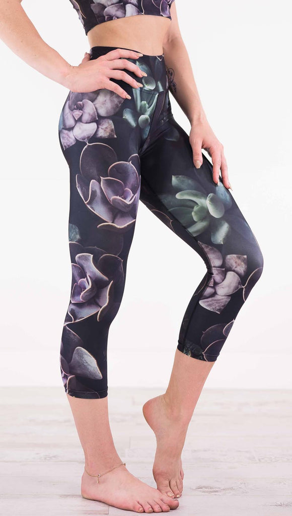 Right view of model wearing black capri leggings with green and purple succulent plants throughout