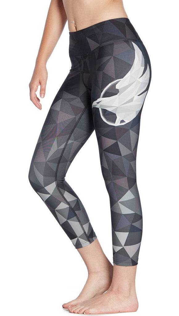 close up left side view of ombre black polygon themed printed capri leggings with large eagle logo motif