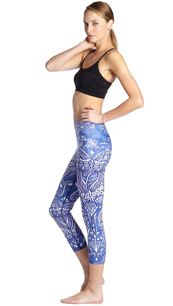 left side view of model wearing blue and white owl themed printed capri leggings