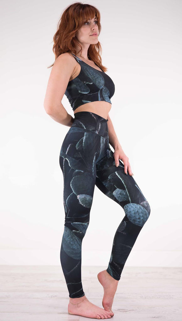 Right view of model wearing black athleisure leggings with dark green cacti plants throughout