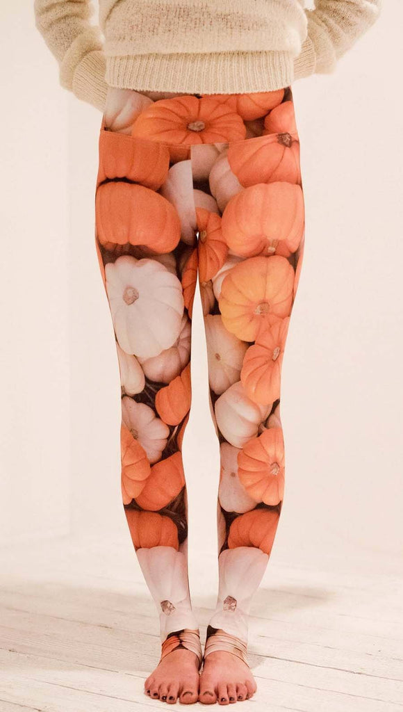 Front view of model wearing white and orange pumpkin leggings